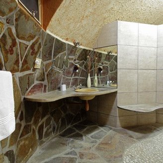 Ein modernes Badezimmer mit einer einzigartigen Steinwand und einem eleganten Waschbecken aus Holz, das Gemütlichkeit ausstrahlt.