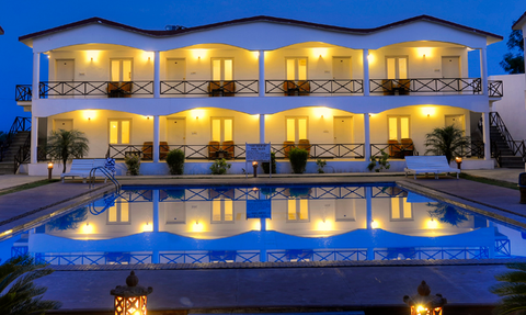 Ein elegantes Resort mit beleuchteten Zimmern spiegelt sich im ruhigen Pool bei Dämmerung wider.