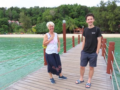 Mutter geht mit ihrem Sohn über eine Holzbrücke am Strand – Malaysia & Borneo mit Kindern