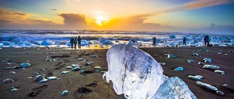 Ein Eisblock liegt bei traumhaftem Wetter am Strand