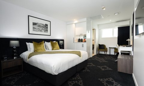 Ein modernes Hotelzimmer mit einem großen Bett, eleganten Kissen und einem gemütlichen Sessel in der Ecke.