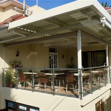 Ein modernes Haus mit einer großzügigen Terrasse, die mit eleganten Stühlen und einem Tisch ausgestattet ist.