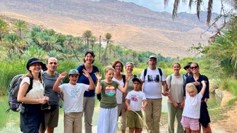 Gruppe posiert für Foto im Wadi Shab mit Bergen im Hintergrund – Oman Familienreise