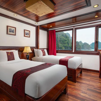 Ein elegantes Zimmer mit zwei Einzelbetten, warmen Holztönen und Blick auf die beeindruckende Landschaft von Ha Long Bay.