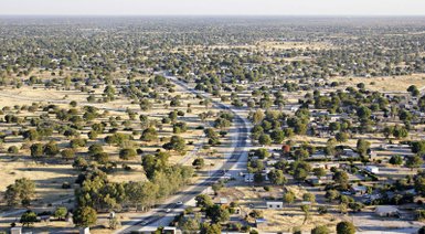 Eine weite Landschaft mit verstreuten Häusern und Bäumen, die sich entlang einer kurvenreichen Straße erstreckt.