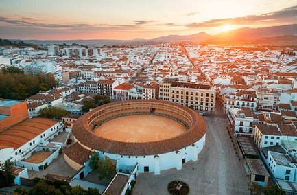 Die Arena von Ronda erhebt sich majestätisch über die Stadt, während die Sonne hinter den Bergen untergeht.