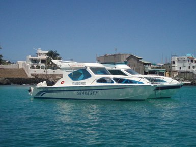 Zwei weiße Schnellboote liegen ruhig im klaren Wasser, umgeben von einem sonnigen, blauen Himmel und einer Küstenlandschaft.