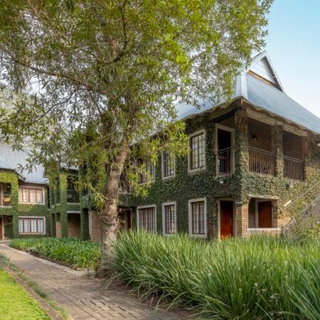 Ein malerisches Gebäude, umgeben von üppigem Grün, mit einem charmanten, begrünten Außenbereich und einem klaren Himmel.