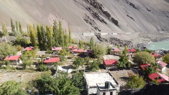 Eine malerische Ansicht eines kleinen Dorfes am Himalaya, umgeben von hohen Bergen und üppiger Vegetation.