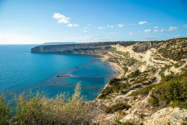 Eine atemberaubende Küstenlandschaft mit klarem, blauem Wasser und sanften Hügeln, die sich entlang der Küste erstrecken.