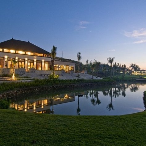 Ein Golfresort in der Abendstimmung, mit einem eleganten Gebäude und einem Teich, der die Umgebung perfekt reflektiert.