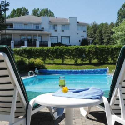 Zwei Liegestühle stehen am Pool, während ein erfrischendes Getränk auf einem Tisch bereitsteht, umgeben von üppigem Grün.