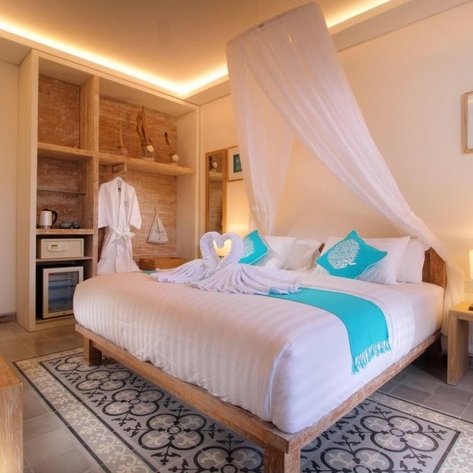 Ein einladendes, helles Zimmer mit betont natürlichem Holzdekor, einem romantisch dekorierten Bett mit Himmel.