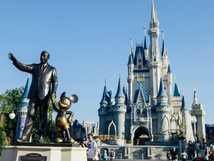 Eine bronzene Statue von Walt Disney und Mickey Mouse steht vor dem majestätischen Schloss im Magic Kingdom.