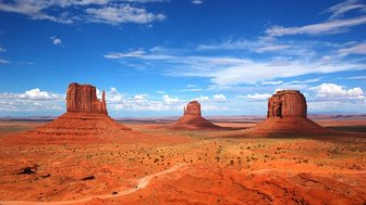 Die beeindruckenden roten Felsen von Monument Valley erheben sich majestätisch unter einem strahlend blauen Himmel.