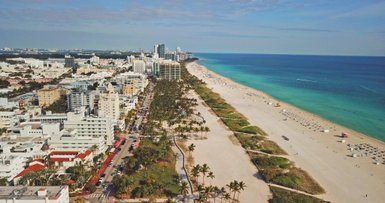 Ein atemberaubender Blick auf den Strand von Miami Beach, gesäumt von Palmen und modernen Gebäuden, unter einem klaren blauen Himmel.