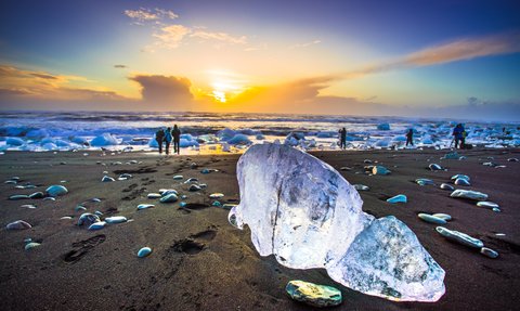 Ein Eisblock liegt bei traumhaftem Wetter am Strand