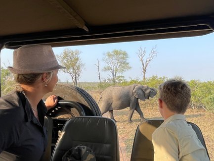 Mutter und Sohn sitzen im Safari-Jeep und beobachten gemeinsam Tiere in der Savanne – Südafrika Familienreise