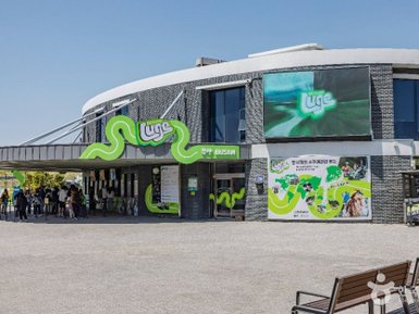 Das moderne Gebäude des Skyline Luge in Busan zeigt eine lebendige grüne Fassade und zahlreiche Besucher an der Kasse.