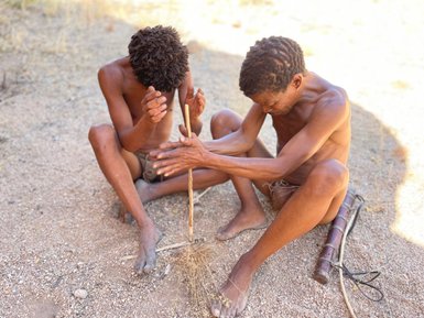 Zwei Männer machen auf traditionelle Weise Feuer - Namibia Urlaub mit Kindern
