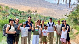 Eine Gruppe mit Familien erkundet die Felslandschaft des Wadi Shab – Oman Reise mit Kindern