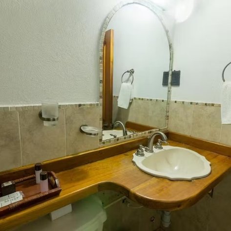 Ein elegantes Badezimmer mit einem geschwungenen Holzwaschtisch und einem großen Spiegel, der den Raum reflektiert.