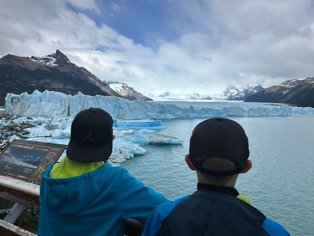 Zwei Kinder stehen am Ufer und blicken auf den beeindruckenden Perito-Moreno-Gletscher im Nationalpark Los Glaciares.