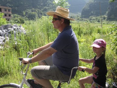 Vater und Kind entdecken gemeinsam die Landschaft von Yangshuo auf einer Fahrradtour – China Familienreise