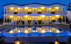 Ein elegantes Resort mit beleuchteten Zimmern spiegelt sich im ruhigen Pool bei Dämmerung wider.