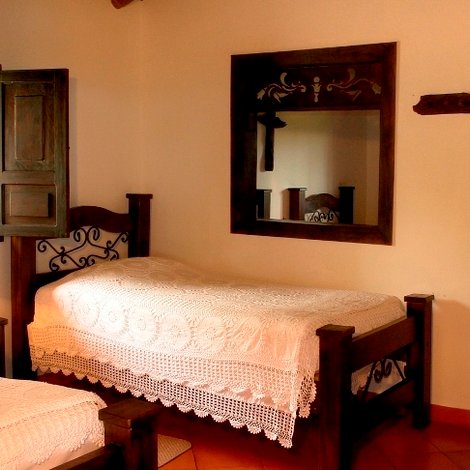 Ein gemütliches Schlafzimmer mit zwei Einzelbetten, einem Nachttisch und einer Lampe, umgeben von grüner Natur.