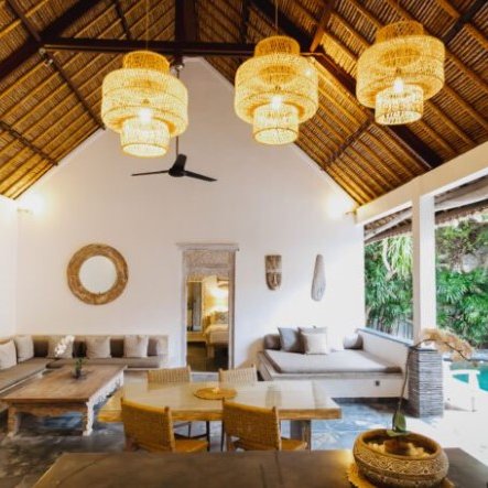 Ein stilvolles Wohnzimmer mit hohen Decken, geflochtenen Lampen und einem Blick auf den Pool im Freien.