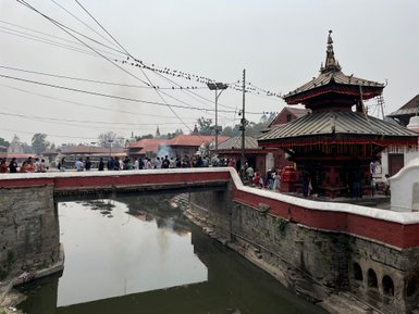 Eine belebte Brücke über den Bagmati-Fluss, umgeben von Menschen, die den Pashupatinath-Tempel besuchen.