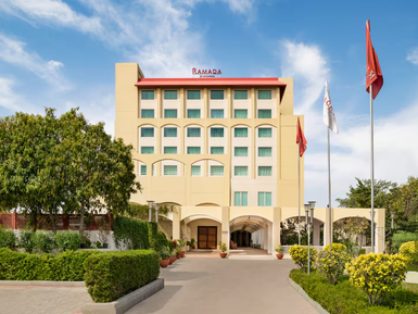 Das Ramada Hotel in Jaipur präsentiert sich mit einer modernen Fassade und einem einladenden Eingangsbereich, umgeben von Grün.