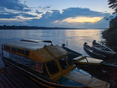 Ein gelbes Boot liegt am Ufer eines ruhigen Flusses, während die Dämmerung den Himmel in sanften Farben erleuchtet.
