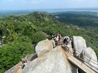 Menschen überqueren eine schmale Brücke mit Blick auf den imposanten Sigiriya-Felsen – Sri Lanka Familienreise