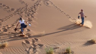 Zwei Kinder erklimmen eine Düne - Namibia Urlaub mit Kindern