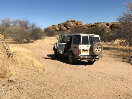 Ein Jeep steht in einer trockenen Landschaft auf einer unbefestigten Straße - Namibia Rundreise mit Kindern