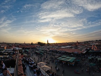 Der belebte Djemaa el Fna Platz in warmes Abendlicht getaucht bei Sonnenuntergang – Marokko mit Kindern