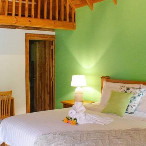 Ein gemütliches Schlafzimmer mit einem großen Bett, umgeben von warmen Holztönen und einer beruhigenden grünen Wand.