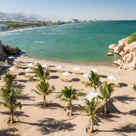 Strand des Crowne Plaza Muscat mit Liegestühlen und Sonnenschirmen – Familienurlaub in Muscat