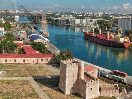 Ein Blick auf die Festung Ozama in Santo Domingo, umgeben von grünen Bäumen und dem glitzernden Wasser des Flusses.