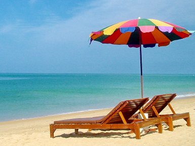 Zwei Liegestühle mit Sonnensschirm am Sandstrand von Khao Lak mit Blick auf das Meer - Thailand Familienreise