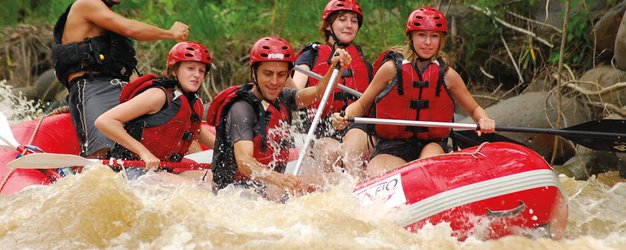 Gemeinsam paddelnde Gruppe im roten Rafting-Boot – Costa Rica Reise mit Kindern