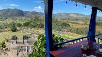 Ein Blick auf die malerische Landschaft von Viñales, mit sanften Hügeln und üppigen Feldern unter einem strahlend blauen Himmel.