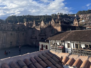Blick auf die Plaza de Armas in Cusco, umgeben von historischen Gebäuden und einem strahlend blauen Himmel.