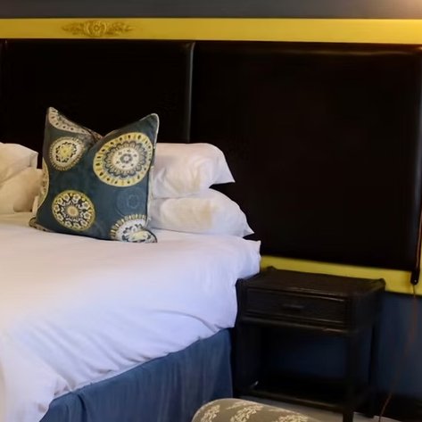Ein stilvolles Schlafzimmer mit einem großen Bett, bunten Kissen und einem eleganten Nachttisch neben dem Bett.