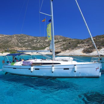 Ein Segelboot schaukelt sanft auf dem klaren, blauen Wasser, während ein pinker Flamingo-Schwimmring daneben schwimmt.