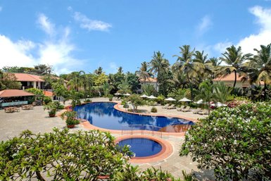Ein weitläufiger Pool umgeben von üppigem Grün und Palmen, ideal für entspannende Tage in Goa.