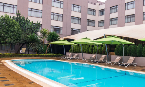 Ein einladender Poolbereich mit grünen Sonnenschirmen und Liegen, umgeben von einem modernen Hotel in Nairobi.