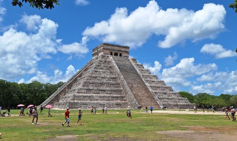 Die beeindruckende Pyramide von Chichén Itzá erhebt sich majestätisch unter einem strahlend blauen Himmel mit weißen Wolken.